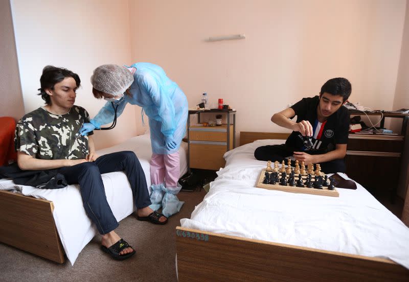 A member of the medical staff wearing protective gear checks the health of chess players from France at a hospital in Murmansk