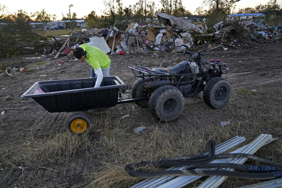 Ricky Trahan uses a four wheeler to move and sort debris on their property, after their home was destroyed by both Hurricane Laura and Hurricane Delta in Lake Charles, La., Friday, Dec. 4, 2020. The family is living in tents, with their son, his fiancee and their one year old son living in a camper. His sister's family's home is now gutted and they are living in a camper on the same property. (AP Photo/Gerald Herbert)