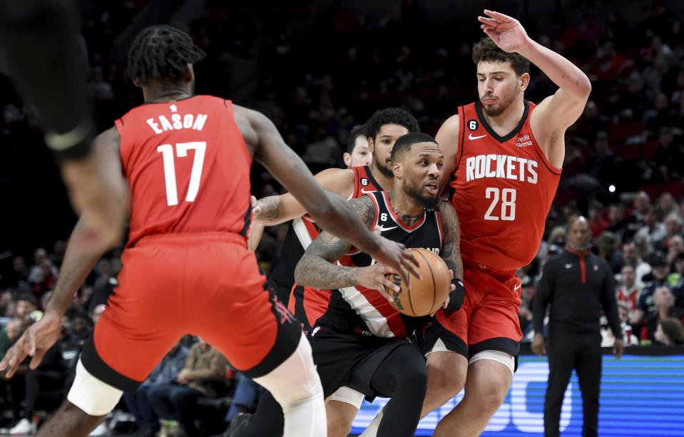 Portland Trail Blazers guard Damian Lillard, center, drives to the basket against Houston Rockets forward Tari Eason, left, and center Alperen Sengun, right, during the second half of an NBA basketball game in Portland, Ore., Sunday, Feb. 26, 2023. Lillard scored a franchise-record 71 points as the Blazers won 131-114. (AP Photo/Steve Dykes)