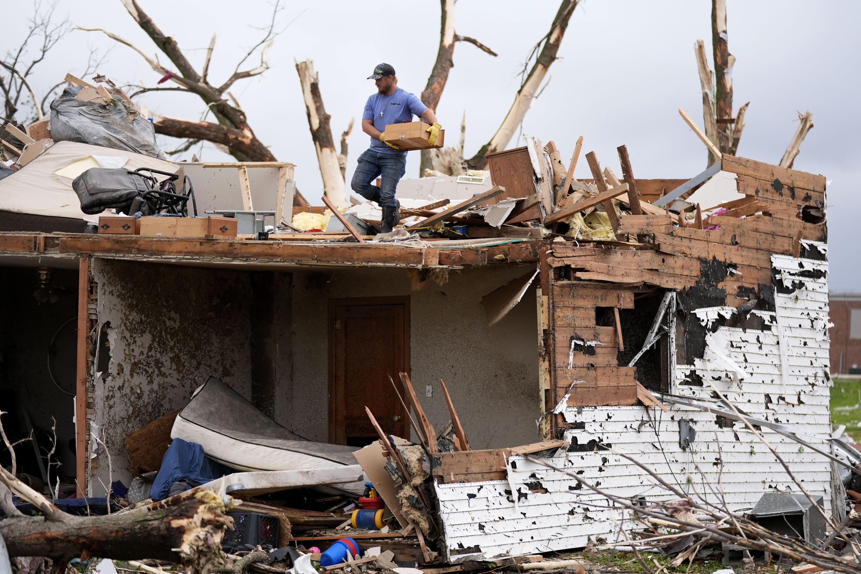 A man sorts through the remains of a home damaged by a tornado on Tuesday in Greenfield, Iowa.