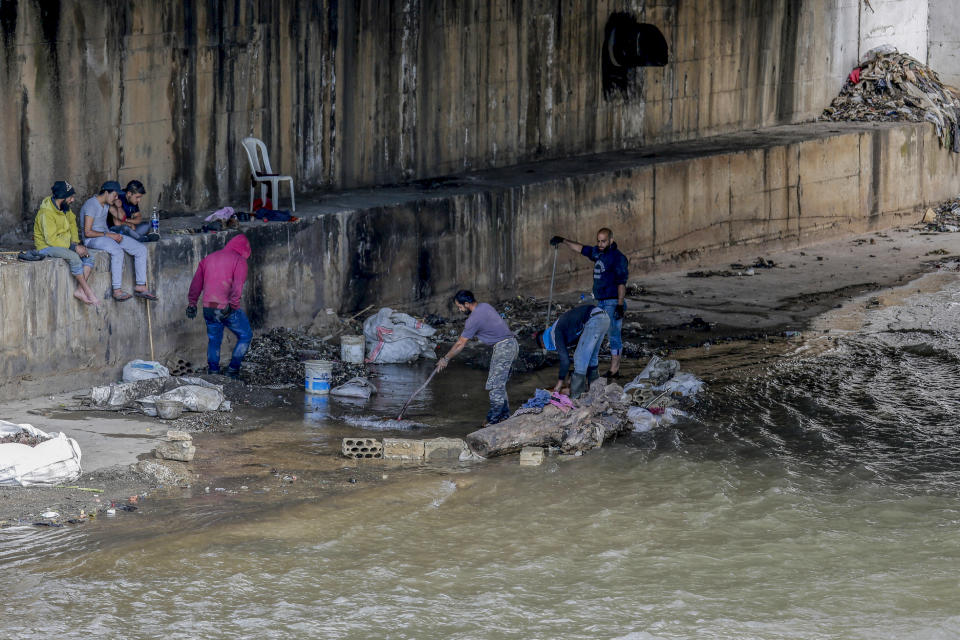 FILE - Men sifts through a sewer for valuables along the foreshore of the Abou Ali River, in the northern city of Tripoli, Lebanon, on May 5, 2020. The World Bank has approved a $300 million additional financing to the poor in Lebanon in which families that live in poverty will get cash payments to help them through the country's historic economic meltdown, the World Bank said in a statement released Friday, May 26, 2023. (AP Photo/Hassan Ammar, File)