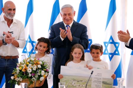 Israeli Prime Minister Benjamin Netanyahu applauds as he is presented with a gift from Israeli residents of the area, at the start of a weekly cabinet meeting in the Jordan Valley, in the Israeli-occupied West Bank