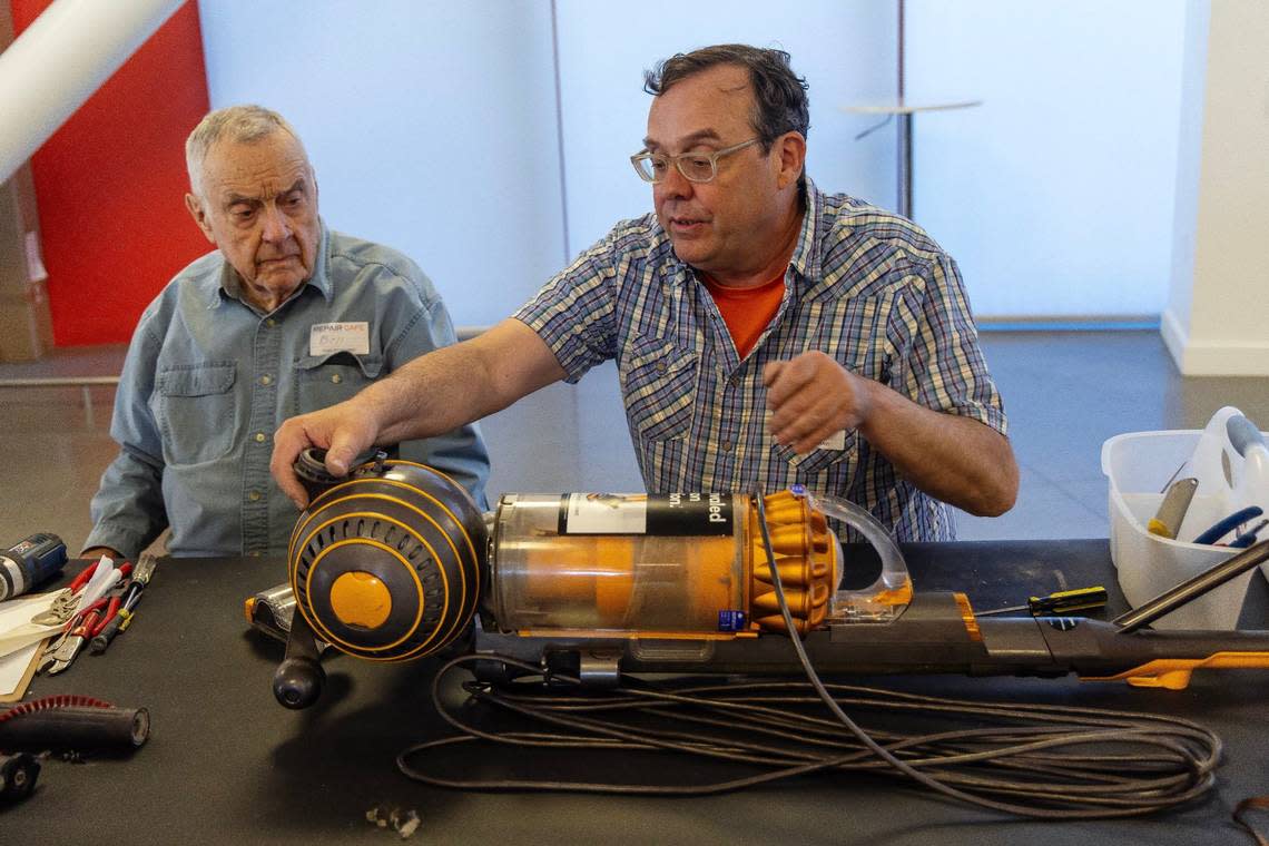 Father-son repair duo Bill Lloyd, left, and John Lloyd, work to repair a vacuum cleaner at Thursday’s “repair cafe.” The pair said the cleaner was overly complicated -- or as they put it, had a “high gizmo factor.”