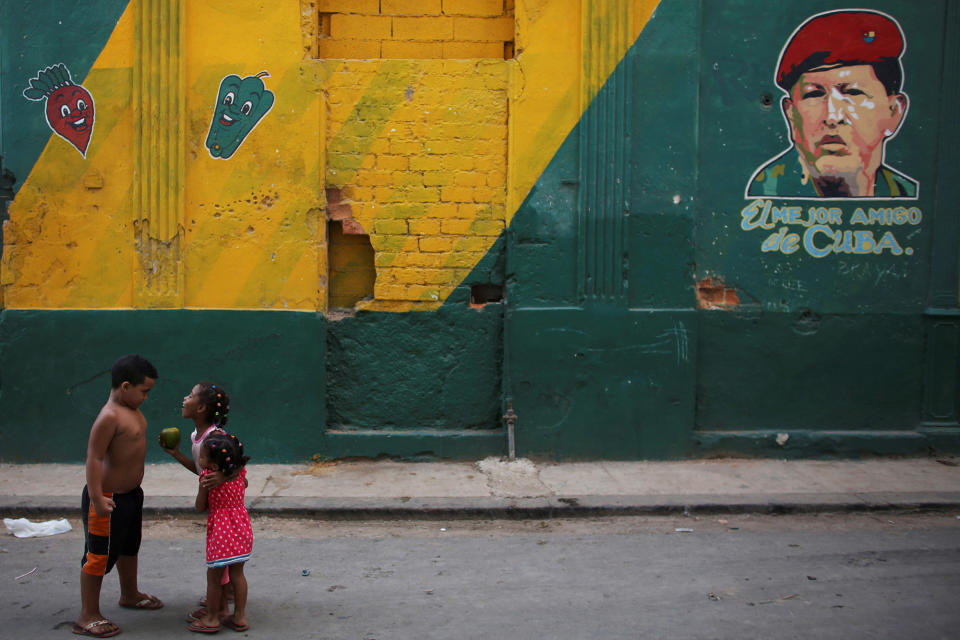Children play next to an image depicting Hugo Chavez