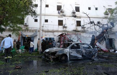 Somali security officers and firefighters are seen at the scene of an attack where a car laden with explosives rammed into a cafeteria in Somalia's capital Mogadishu, May 8, 2017. REUTERS/Feisal Omar