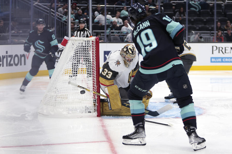 Vegas Golden Knights goaltender Adin Hill blocks a shot as Seattle Kraken left wing Jared McCann and center Ryan Donato (9) look for a rebound during the second period of an NHL hockey game Saturday, Oct. 15, 2022, in Seattle. (AP Photo/Jason Redmond)