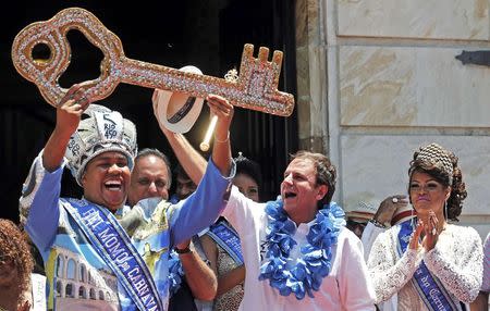 Rio de Janeiro's Mayor Eduardo Paes (2nd R) hands over the city's ceremonial key to the Rei Momo, or Carnival King Wilson Neto (L) at Cidade Palace in Rio de Janeiro February 13, 2015. REUTERS/Sergio Moraes