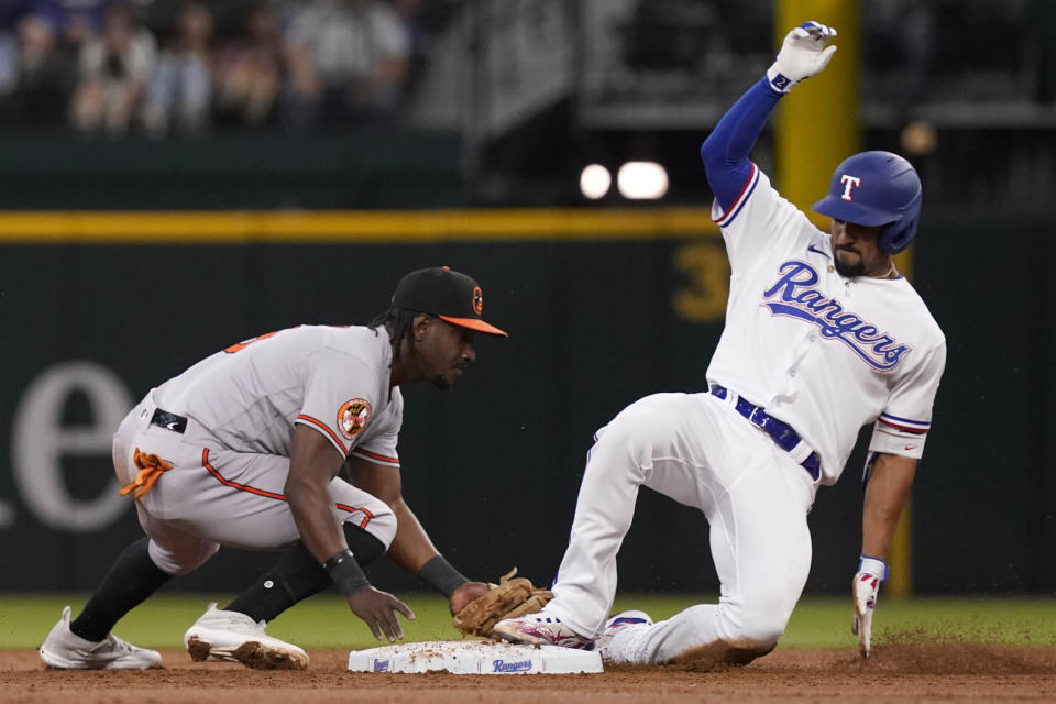 Texas Rangers' Marcus Semien, right, beats the tag by Baltimore Orioles shortstop Jorge Mateo (3) to reach second base on a throwing error to first base during the third inning of a baseball game in Arlington, Texas, Wednesday, April 5, 2023. (AP Photo/LM Otero)