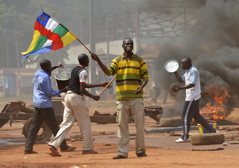 A man waves a Central African flag as others block a road during a protest against the French "Operation Sangaris" military intervention in the Galabadia neighborhood of Bangui on December 22, 2013
