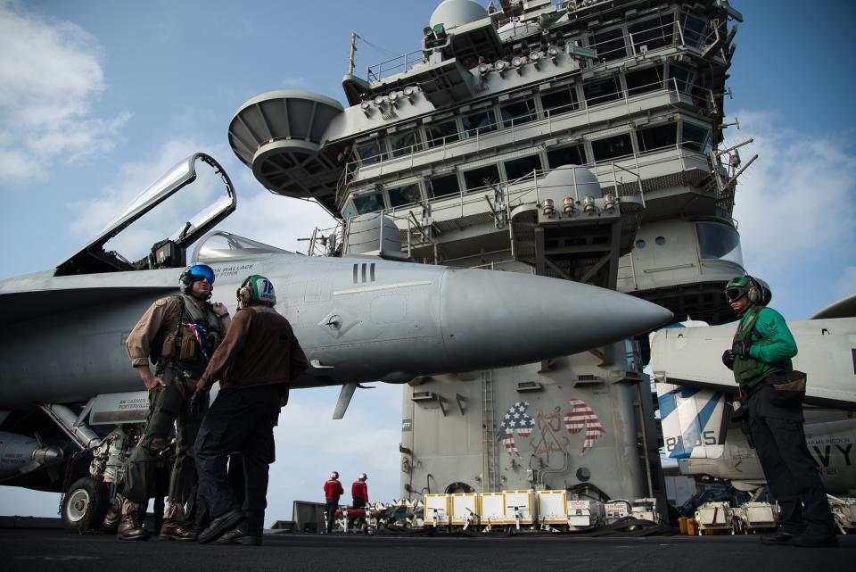 FILE - In this June 3, 2019 file photo, a pilot speaks to a crew member by an F/A-18 fighter jet on the deck of the USS Abraham Lincoln aircraft carrier in the Arabian Sea. The U.S. Navy is trying to put together a new coalition of nations to counter what it sees as a renewed maritime threat from Iran. Meanwhile, Iran finds itself backed into a corner and ready for a possible conflict. It stands poised on Friday, Sept. 6, 2019, to further break the terms of its 2015 nuclear deal with world powers. (AP Photo/Jon Gambrell, File)