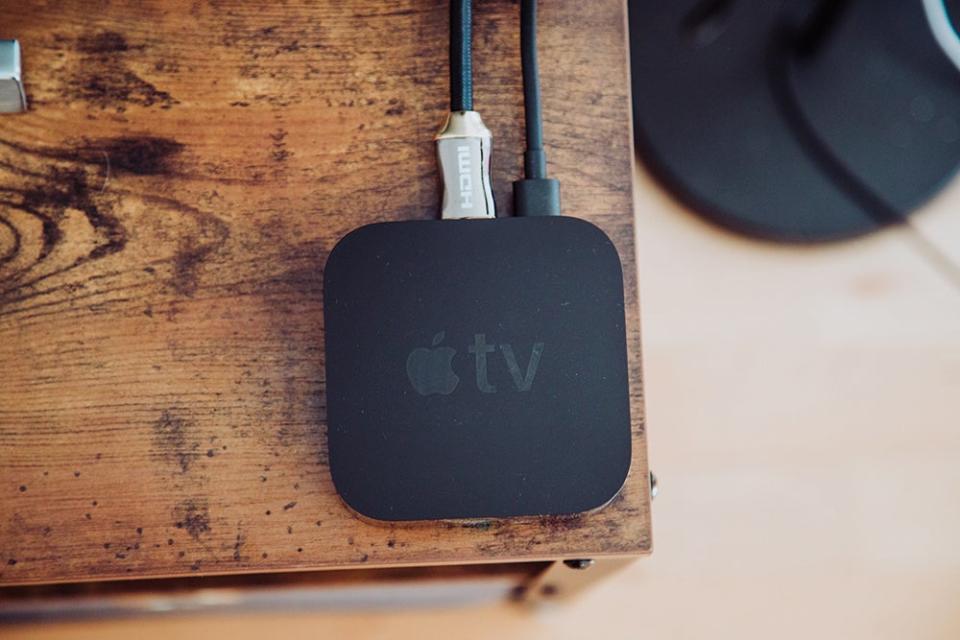 Apple TV media player on a wood table.