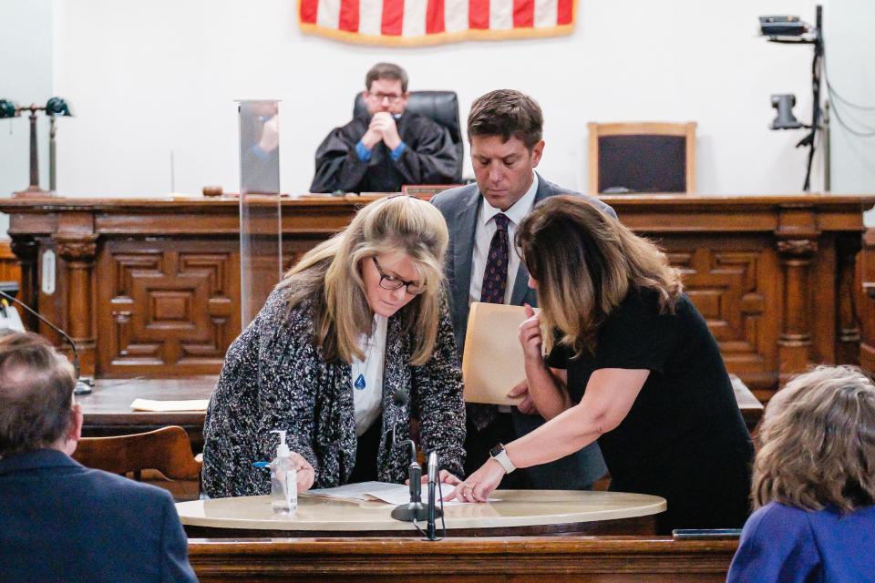 Mary J. Pozderac, at left, signs a plea form during her arraignment in front of Carroll County Common Pleas Judge Michael V. Repella II.