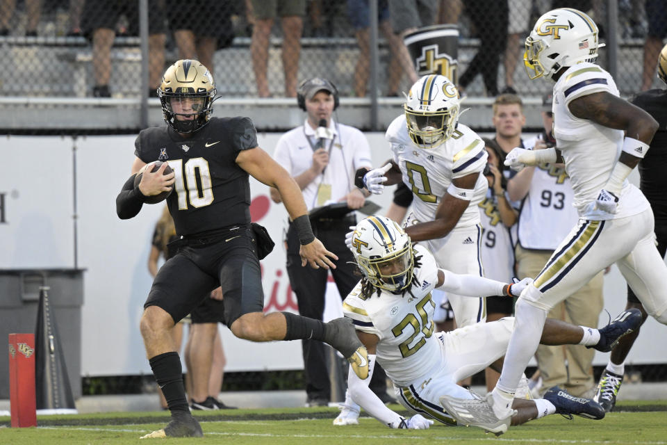 Central Florida quarterback John Rhys Plumlee (10) rushes for a 28-yard touchdown past Georgia Tech defensive backs LaMiles Brooks (20), Myles Sims (0) and Zamari Walton, right, during the second half of an NCAA college football game, Saturday, Sept. 24, 2022, in Orlando, Fla. (AP Photo/Phelan M. Ebenhack)