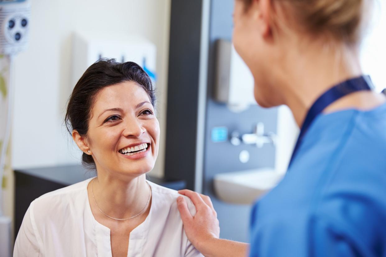 Female patient being reassured by doctor in hospital room.