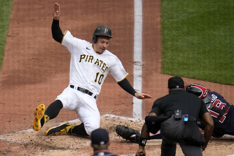 Pittsburgh Pirates' Bryan Reynolds (10) scores past Atlanta Braves catcher Travis d'Arnaud, obscured behind umpire Alan Porter, right, on a sacrifice fly by Alonso Rivas during the third inning of a baseball game in Pittsburgh, Thursday, Aug. 10, 2023. (AP Photo/Gene J. Puskar)