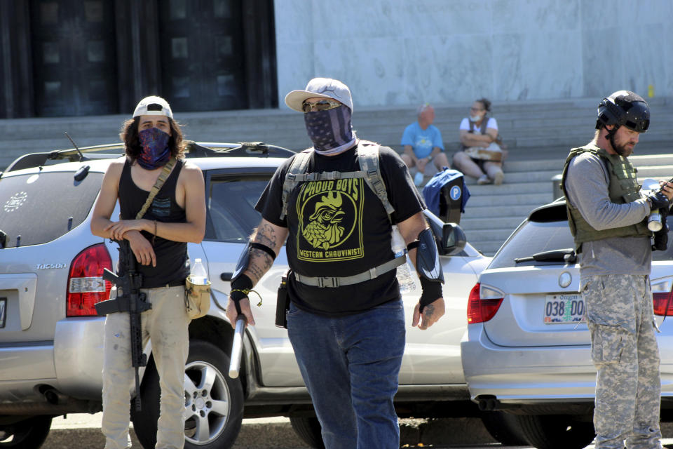 A protester wearing a t-shirt of a far-right group taunts Black Lives Matter protesters across the street in front of the Oregon State Capitol in Salem, Ore., on Monday, Sept. 7, 2020. Hundreds of people gathered on Labor Day in a small town south of Portland for a pro-President Donald Trump vehicle rally, just over a week after member of a far-right group was fatally shot after a Trump caravan went through Oregon's largest city. Later, pro-Trump supporters and counter-protesters clashed at Oregon's Capitol. (AP Photo/Andrew Selsky)