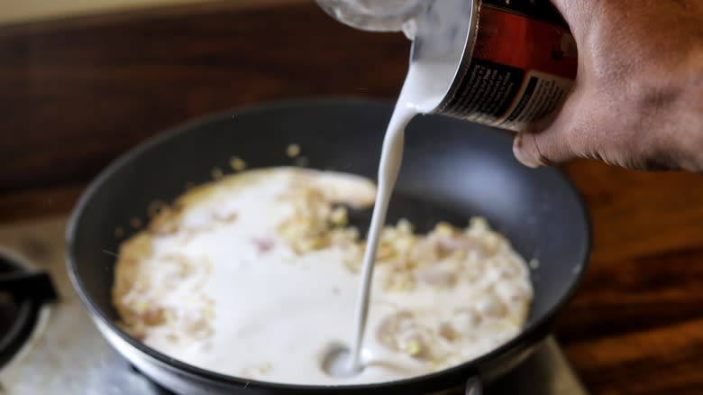 pouring coconut milk into skillet