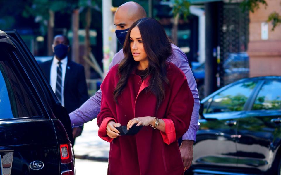 Meghan, wearing a vivid red suit, visited the school to read to pupils - Gotham/GC Images