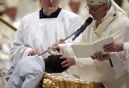 Pope Francis baptizes a young boy during the Easter vigil mass in Saint Peter's basilica at the Vatican, April 15, 2017. REUTERS/Max Rossi