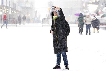 A woman takes a photo during a snowstorm in Times Square in New York January 21, 2014. REUTERS/Brendan McDermid