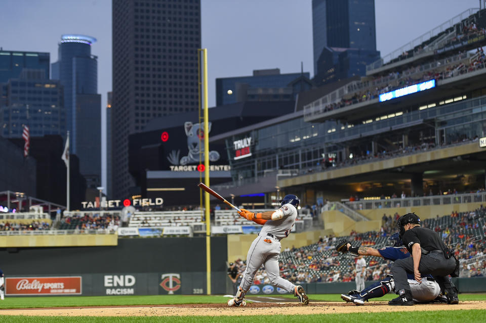 Houston Astros Jeremy Pena, left, hits a sacrifice fly to right field scoring a run as Minnesota Twins catcher Gary Sanchez and home plate umpire Chris Segal look on during the second inning of a baseball game, Wednesday, May 11, 2022, in Minneapolis. (AP Photo/Craig Lassig)