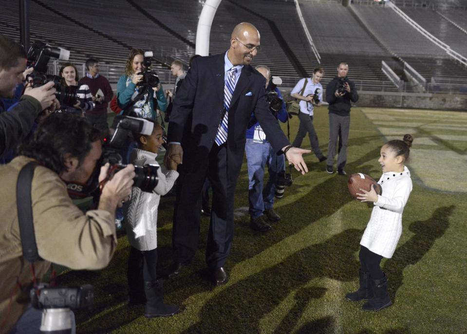 Penn State's new football coach James Franklin prepares to catch a football from his daughter, Addison, 5, after being introduced during an NCAA college football news conference at Beaver Stadium, Saturday, Jan. 11, 2014, in State College, Pa. Holding her father's hand is Shola, 6. (AP Photo/John Beale)