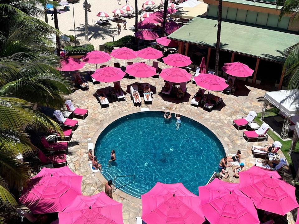 Pool with pink umbrellas around it at the Royal Hawaiian hotel.