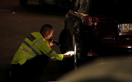 A police officer inspects a car at the scene of a fatal road traffic collision in the carpark of the Ibis Budget Hotel in Salford, Britain, August 10, 2017. REUTERS/Andrew Yates