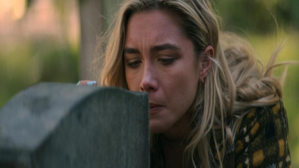 A woman looking at a gravestone.