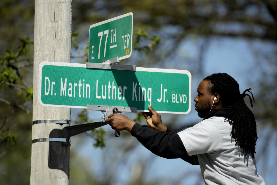 FILE - In this April, 20, 2019, file photo, public works employee Jerry Brooks changes a street sign from The Paseo to Dr. Martin Luther King Jr. Blvd. in Kansas City, Mo. More than 50 years after King was assassinated, the city's efforts to honor the civil rights leader has met opposition from citizens opposed to the renaming of The Paseo, one of the city's iconic boulevards. (AP Photo/Charlie Riedel, File)