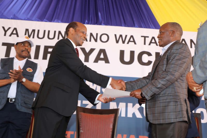 Tanzania's re-elected President John Pombe Magufuli receives his winning certificate from the Chairman of the National Electoral Commission (NEC) Semistocles Kaijage at the Commission (NEC) headquarters within the Njedengwa suburb in Dodoma