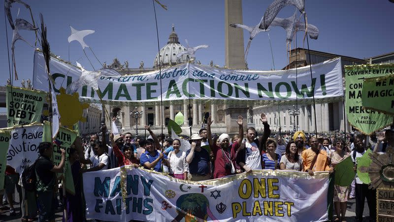 People hold banners reading “Climate action Now” and “Many Faiths, One Planet” in St. Peter’s Square, at the Vatican on June 28, 2015. Greeting people Sunday from his studio window, Francis praised a few hundred people who marched to St. Peter’s Square under the banner “one Earth, one family.”