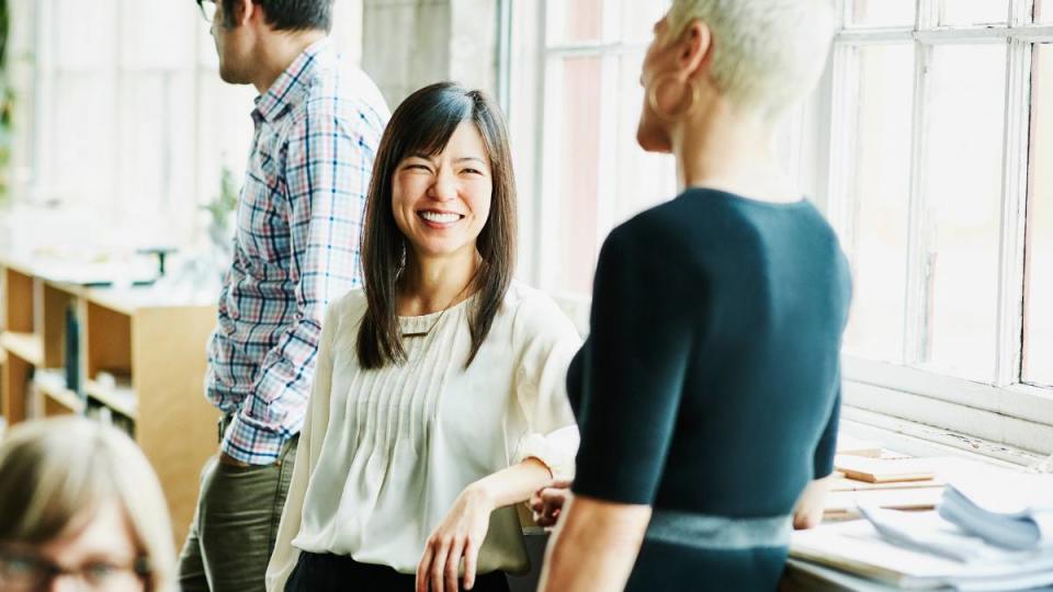 how to reduce stress at work: Smiling coworkers in discussion in design studio