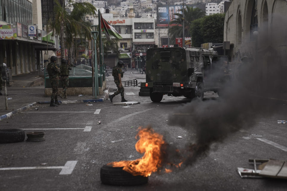 Palestinian security forces clash with Palestinians following an arrest raid against local militants, in the West Bank city of Nablus Tuesday, Sept. 20, 2022. Palestinian security forces on Tuesday exchanged fire with militants in the center of the West Bank's second-largest city, as angry residents pelted an armored jeep with objects and chased it away. One man was reported dead. The incident, sparked by an arrest raid against local militants, marked a rare case of deadly internal Palestinian fighting in the occupied West Bank. (AP Photo/Nasser Nasser)