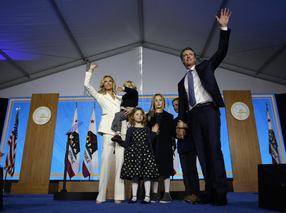 FILE -- In this Jan. 7, 2019 file photo, California Governor Gavin Newsom, his wife, Jennifer Siebel Newsom, and family waves after taking the oath office during his inauguration as 40th Governor of California, Sacramento, Calif. Siebel Newsom has shunned the traditional title of "first lady" and is focusing on women's issues including equal pay and expanding family leave. (AP Photo/Rich Pedroncelli, File)