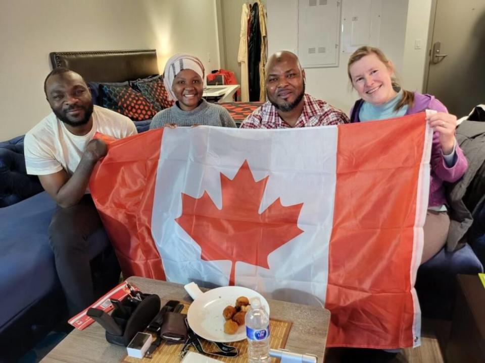 Seidu Mohammed, from left, Mariam Mohammed, Razak Iyal and Laurel Martin pose with a Canadian flag to mark Seidu and Razak's steps toward becoming citizens of the country. The two women have supported the duo in making a life for themselves in Winnipeg. (Submitted - image credit)