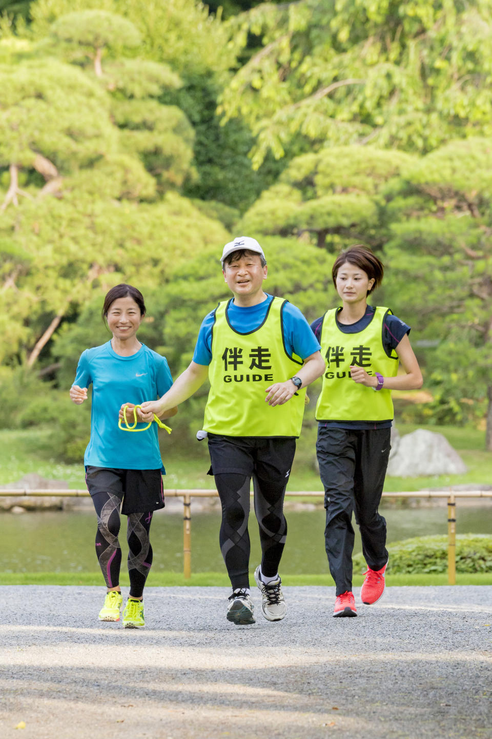 In this June 26, 2018, photo provided by the Imperial Household Agency of Japan, Japan's Crown Price Naruhito guides Rio Paralympics women's T12 marathon silver medalist Misato Michishita as they run together at Akasaka Imperial Garden in Tokyo. Naruhito celebrates his 59th birthday on Saturday, Feb. 23, 2019. (Imperial Household Agency of Japan via AP)