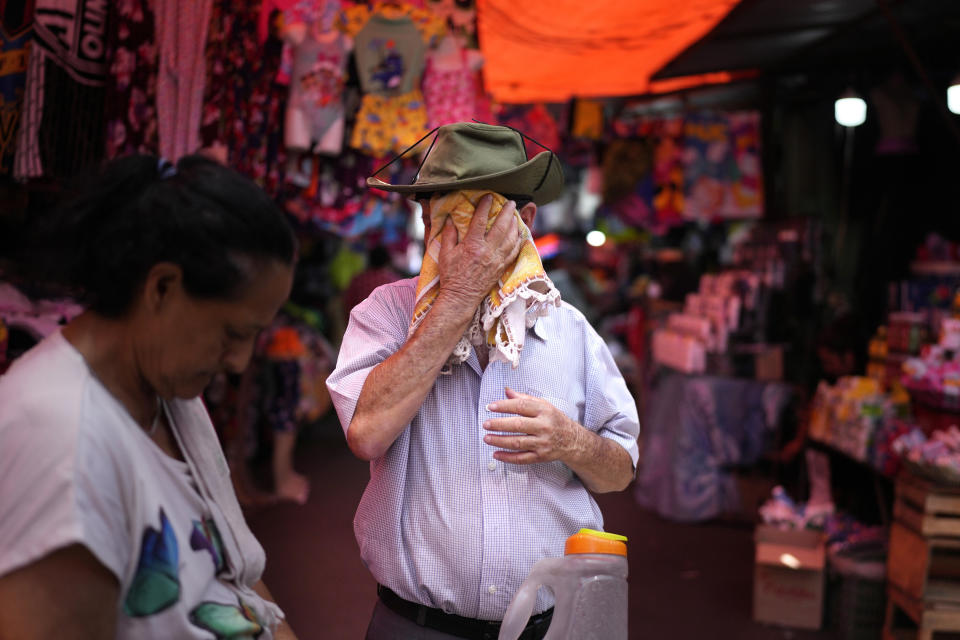 A Market 4 juice vendor wipes sweat from his face on a hot summer day in Asuncion, Paraguay, Tuesday, Jan. 16, 2024. While the U.S. is shivering through bone-chilling cold, most of the rest of world is feeling unusually warm weather. Scientists Tuesday say that fits with what climate change is doing to Earth. (AP Photo/Jorge Saenz)