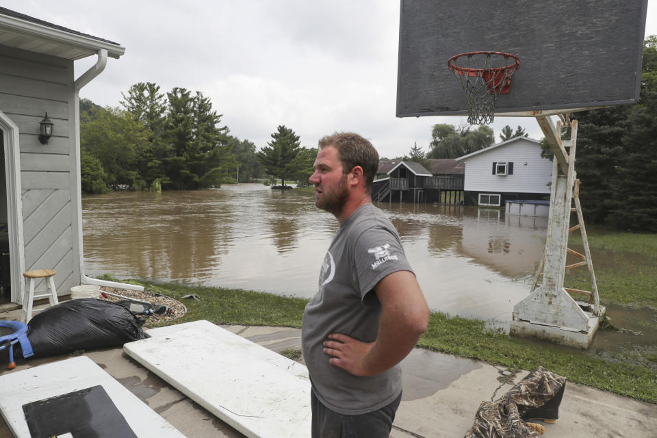 Tyler Statz takes a break from cleaning out his flooded home Tuesday, Aug. 21, 2018, in Black Earth, Wis. Black Earth Creek hit record flood stage with evacuations underway in Black Earth, Cross Plains and Mazomanie, according to Dane County Emergency Management. (Steve Apps/Wisconsin State Journal via AP)