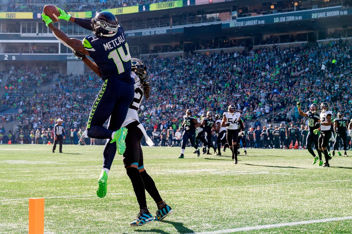 Seattle Seahawks wide receiver DK Metcalf (14) catches pass from quarterback Geno Smith (7) as Jacksonville Jaguars cornerback Shaquill Griffin (26) defends during the second quarter of an NFL game on Sunday at Lumen Field in Seattle. Metcalf would score on the play.