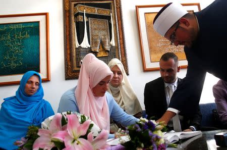 Bosnian Muslim bride puts her signature in the marriage document during collective Sharia wedding ceremony for sixty couples in Sarajevo, Bosnia and Herzegovina July 19, 2018. REUTERS/Dado Ruvic