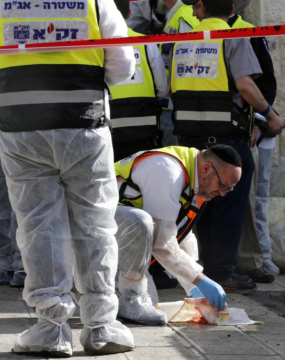 A member of the Zaka emergency response team cleans blood from the ground outside Jerusalem synagogue