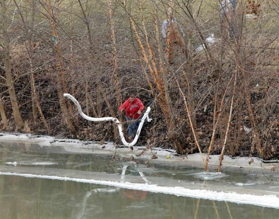 A Freedom Industries worker places a boom in the Elk River Thursday, Jan. 9, 2014, at the site of a chemical leak in Charleston that has fouled the drinking water in five West Virginia counties. (AP Photo/The Charleston Gazette, Chris Dorst)
