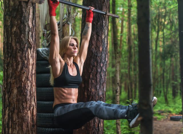 fit woman doing hanging leg raises, concept of core exercises for sculpted abs