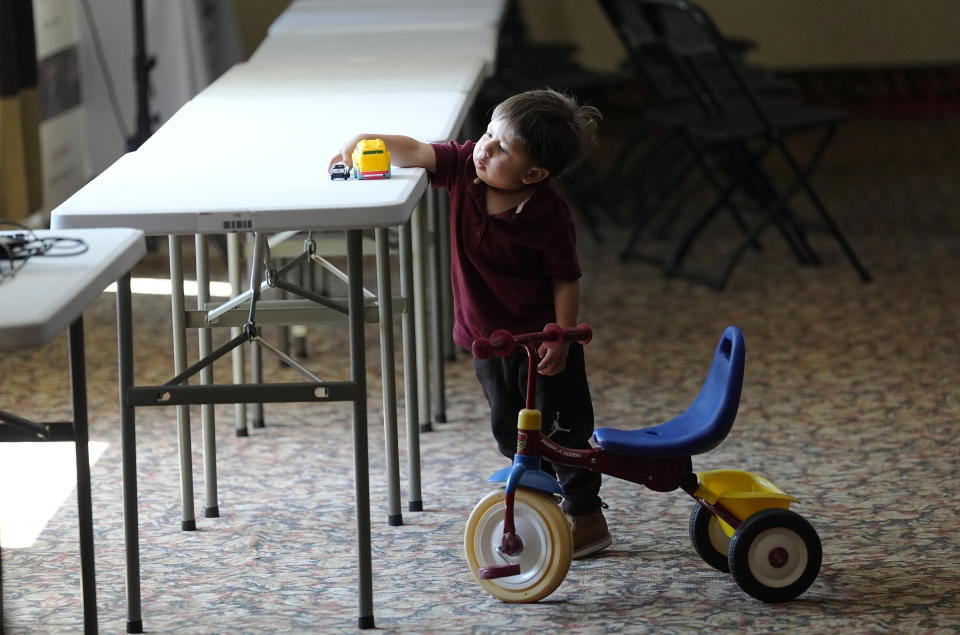 Two-year-old Rodrigo Guacapan plays with his toy vehicles as his parents attend an an orientation session for recent immigrants, Monday, May 20, 2024, in Denver. (AP Photo/David Zalubowski)