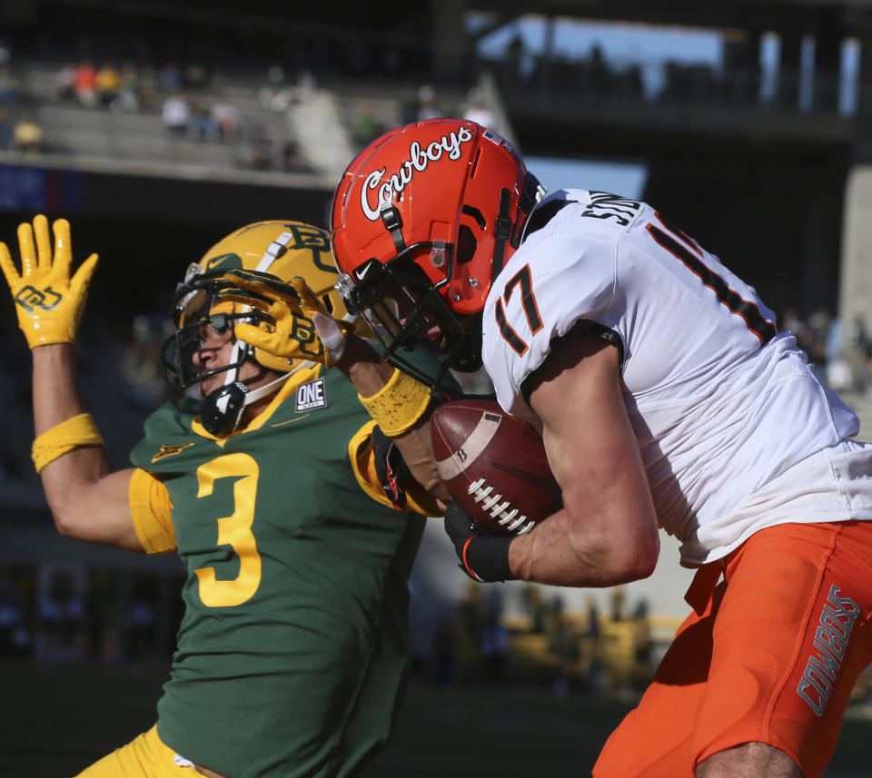 Oklahoma State wide receiver Dillon Stoner, right, pulls down a touchdown pass over Baylor cornerback Raleigh Texada, left, in the first half of an NCAA college football game, Saturday, Dec. 12, 2020, in Waco, Texas. (Rod Aydelotte/Waco Tribune-Herald via AP)