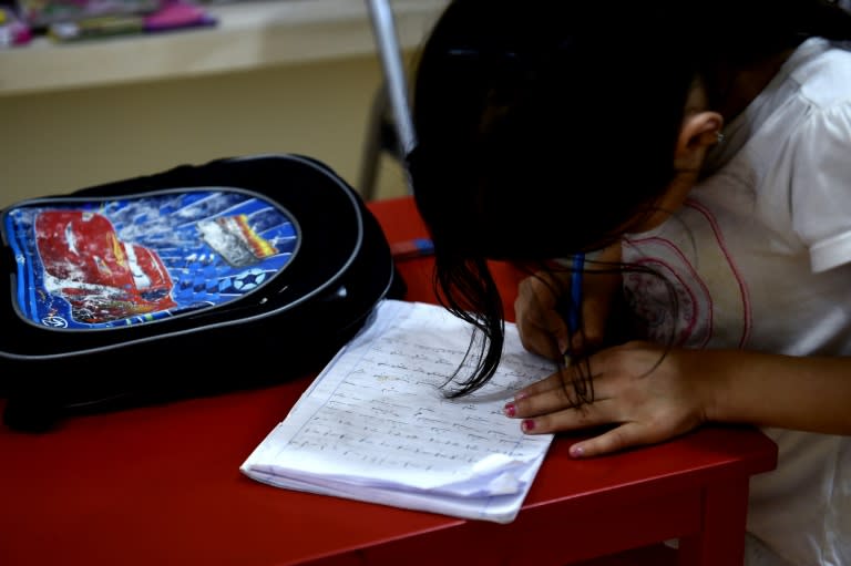 A refugee girl writes at a library set up on the premises of an international non-governmental organisation (NGO) hosting Syrian and Afghan women and children, in central Athens