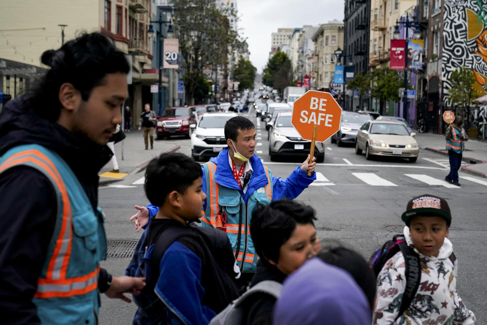 Hung Truong, background, with Safe Passage makes sure children make it safely to the Boys & Girls Clubs of San Francisco for after-school programs Wednesday, March 27, 2024, in San Francisco. (AP Photo/Godofredo A. Vásquez)