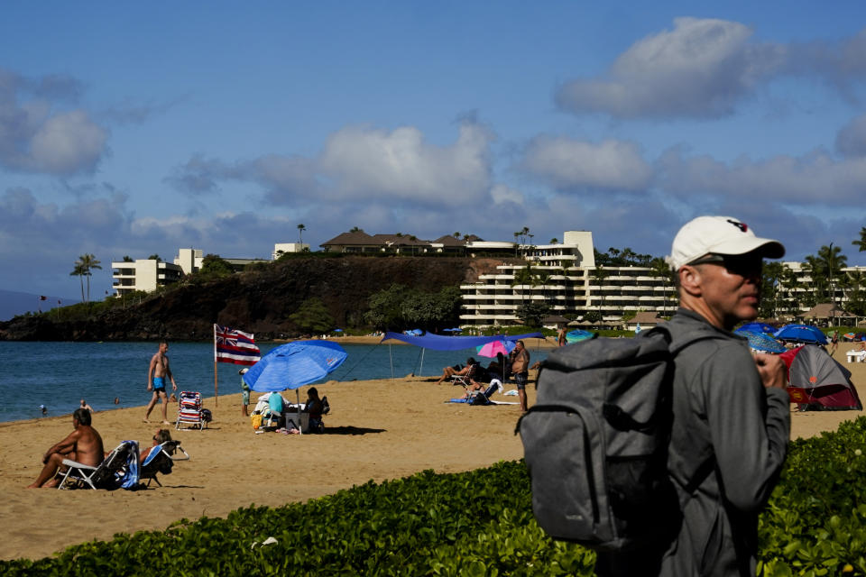 Tourists visit Kaanapali Beach, Wednesday, Dec. 6, 2023, in Lahaina, Hawaii. Residents and survivors still dealing with the aftermath of the August wildfires in Lahaina have mixed feelings as tourists begin to return to the west side of Maui. (AP Photo/Lindsey Wasson)