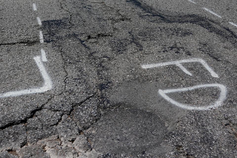Vehicles travel northbound on Fairbanks Avenue over crumbling pavement marked for repair in the Sedamsville neighborhood of Cincinnati on July 18.